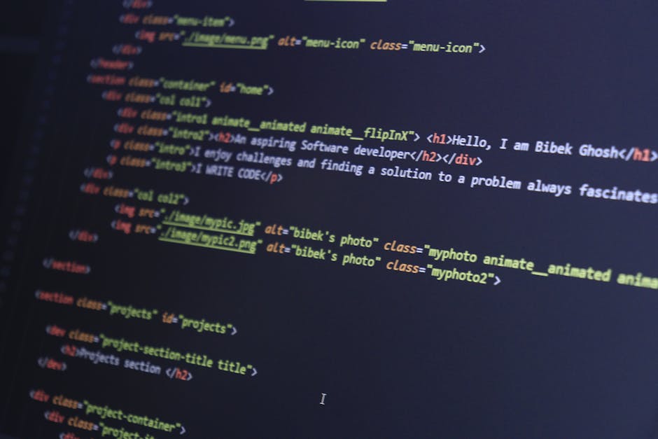 A close-up image of a person's hand typing on a silver laptop keyboard placed on a wooden desk. The screen displays lines of code or programming text in a dark background with colorful syntax highligh